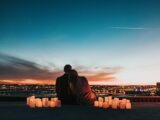 couple sitting on the field facing the city