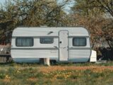 white and gray camper trailer on green grass field