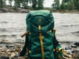 green and black backpack on brown wooden log