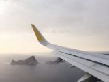 airplane wing above body of water during daytime