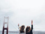 two women making peace sign near the Golden Gate bridge