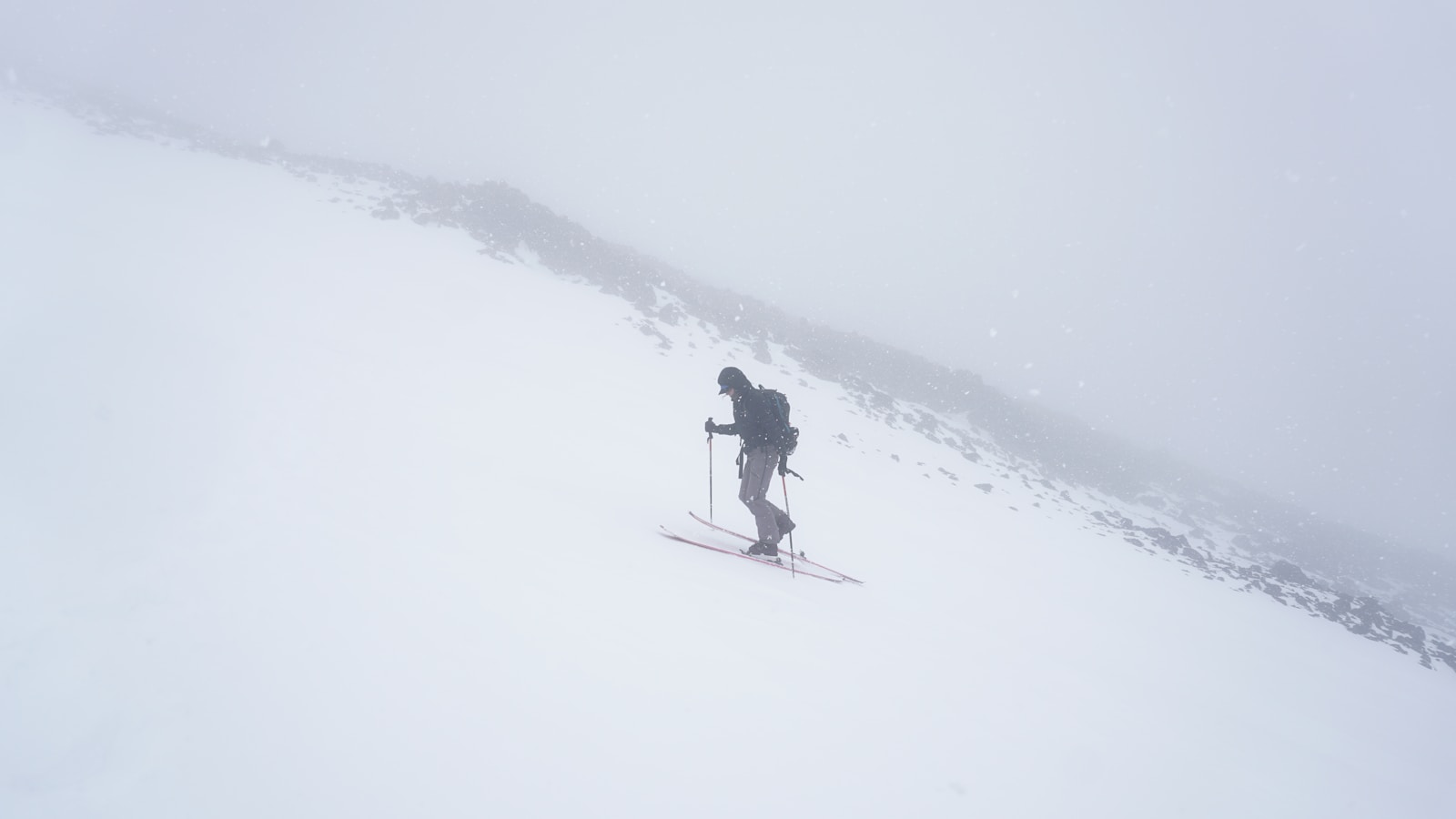 A person walking up a snowy hill on skis